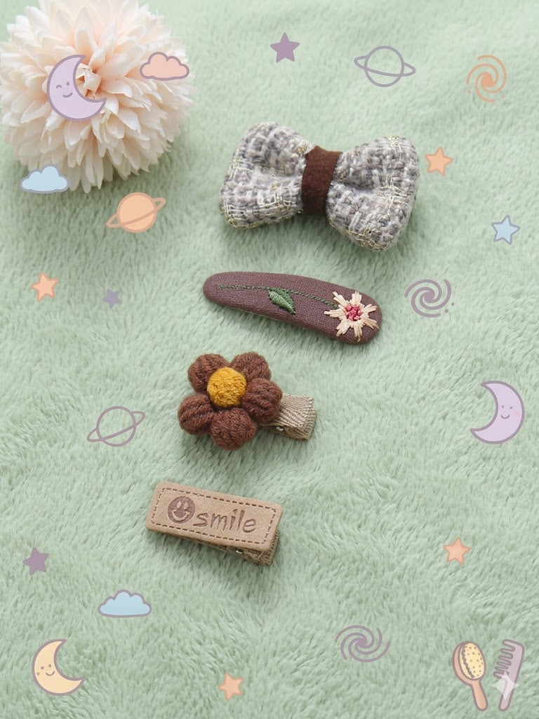 Set of decorative hair clips including a bow, flower, and heart shape on a light background.