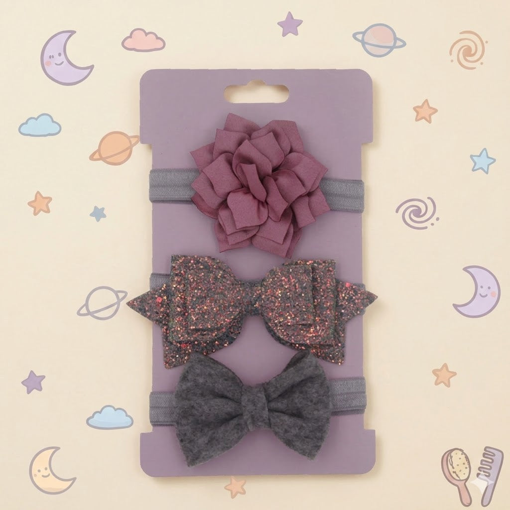 Set of hair accessories including a pink flower, glittery bow, and grey bow on a pink card.