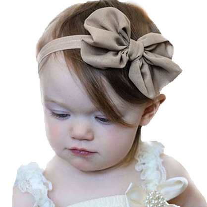 Child wearing a beige headband with a large bow