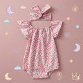 Floral baby romper with matching headband on a pink background with decorative elements.