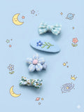 Set of decorative hair clips on a blue background with celestial illustrations.
