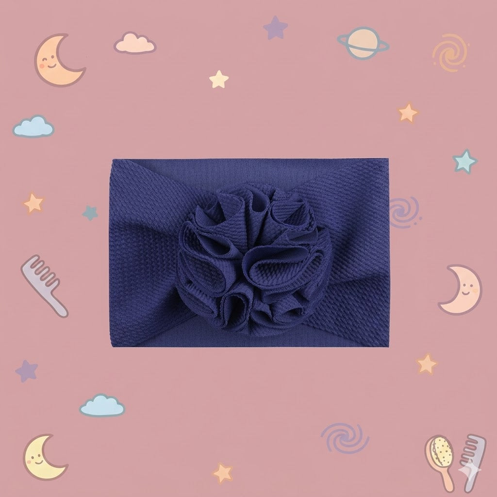 Navy blue headband with a floral accessory on a pink background