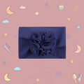 Navy blue headband with a floral accessory on a pink background